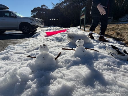 Two small snowmen standing in patch of melting snow