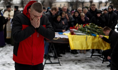 A friend reacts next to a coffin with the body of Ukrainian decathlete and serviceman Volodymyr Androshchuk, who was recently killed in a fight against Russian troops near Bakhmut