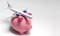 A conceptual image of an aeroplane on top of a piggy bank