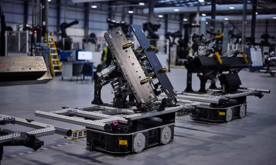 Two small autonomous wheeled robots with components piled on them rolling along