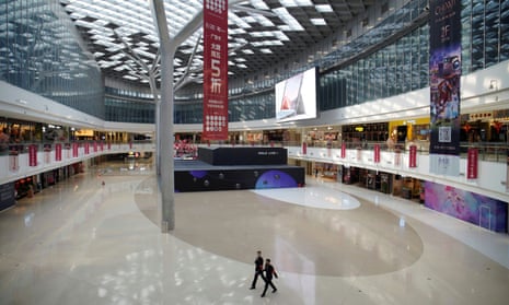 Security staff wearing masks walk in an empty shopping mall in Beijing.