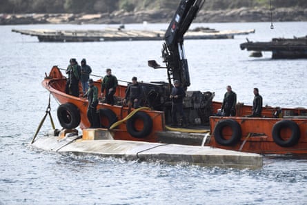 Spanish Guardia Civil stand as boat crew members tie an alleged narco-submarine before towing it, off Illa de Arousa, in Galicia region, northwestern Spain, in March 2023.