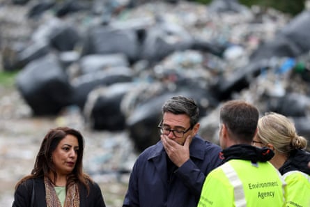 Naz Shah and Andy Burnham talk to people in yellow hi-vis jackets in front of a massive pile of black rubbish bags