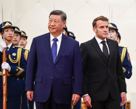 China's President Xi Jinping (L) stands next to France's President Emmanuel Macron during a welcome ceremony at the Great Hall of the People in Beijing.
