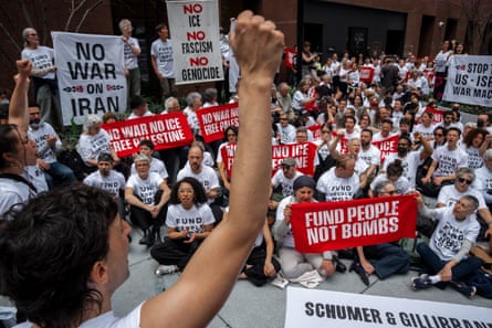 a person raises their fist near a crowd of people holding anti-war banners