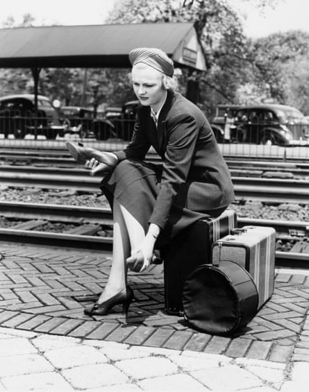 Woman at a train station changing shoes.