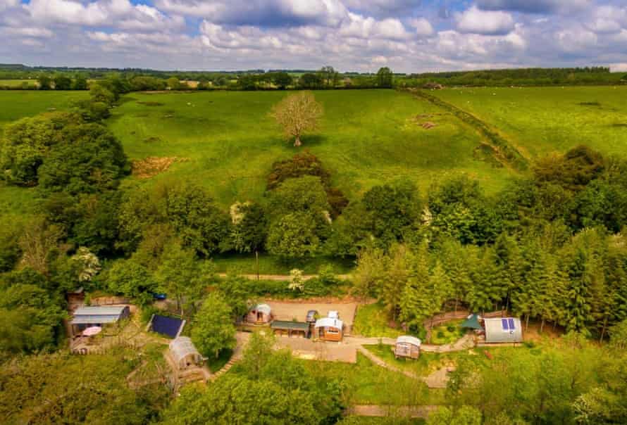Daytime aerial view of Devon Dens cabins and the surrounding woodland.
