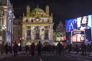 Members of the public watch Voyage by Camille Gross and Leslie Epsztein in Piccadilly Circus.