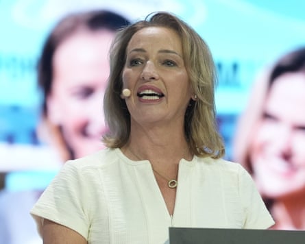 Sarah Pochin speaks mid-sentence with a headset microphone, wearing a cream blouse
