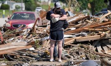 Local residents hug in front of their tornado damaged home in Greenfield, Iowa.