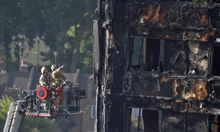 Firefighters inspect the fire damage to the Grenfell Tower block