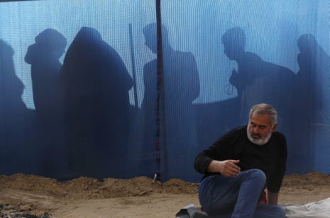 A man sits on the floor at a makeshift shelter in Deir al-Balah 