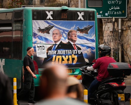 A Jerusalem bus displays a Likud ad of Netanyahu and Trump beside fighter jets, as pedestrians pass