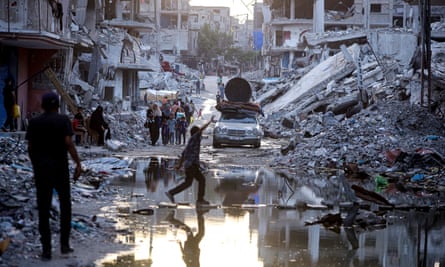 Palestinians displaced by the Israeli air and ground offensive in the Gaza Strip walk past sewage flowing into the streets of the southern town of Khan Younis.