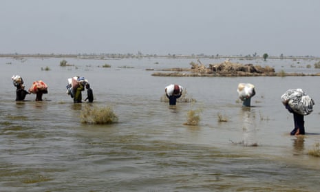 People in Pakistan carry relief aid through flood water.