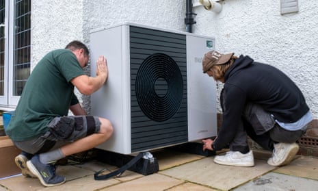 Two people install an air-source heat pump