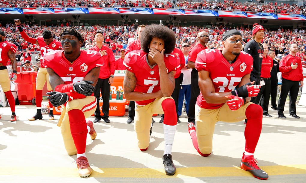 Colin Kaepernick, flanked by Eli Harold and Eric Reid, takes a knee