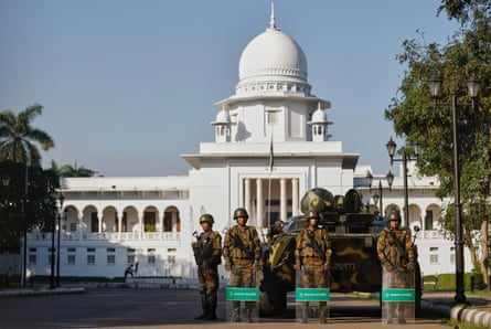 Four soldiers, three with riot shields, stand in front of an armoured vehicle parked outside the white, domed supreme court building