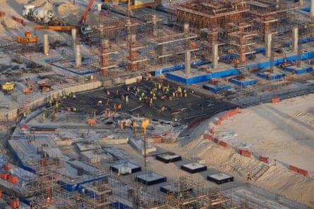 A building site with cranes and the outline of a stadium
