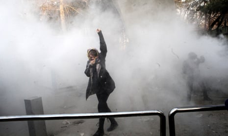 A woman raises her fist as Iranian students clash with riot police during anti-government protests