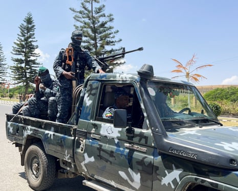 Armed officers ride in a camouflage pickup truck during a patrol