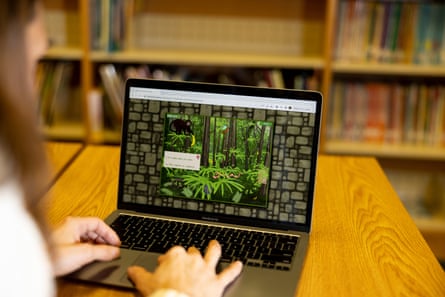 A laptop runs an education game while a woman uses the keyboard.
