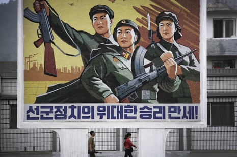North Koreans pass a mural in Wonsan celebrating Songun, the ‘military-first’ policy that allocates resources to the armed forces.