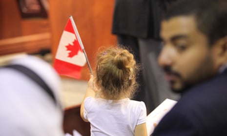 A little girl raising national flag in a Canadian citizenship ceremony in Kitchener, Ontario.