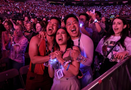 three people cheer in center of pic as crowd around them sings