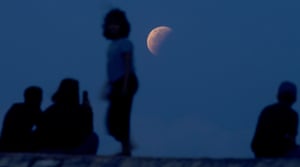Residents watch the lunar eclipse at Sanur beach in Bali, Indonesia