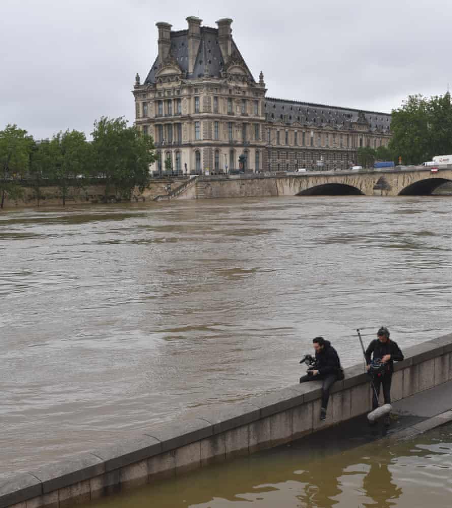 Two photographers take pictures of the Louvre Museum on the other side of the river Seine in Paris.