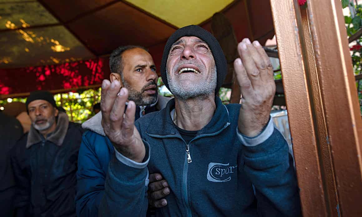 A Palestinian man cries with his hands and eyes raised to the sky