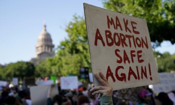a person holds a sign that reads "make abortion safe again"