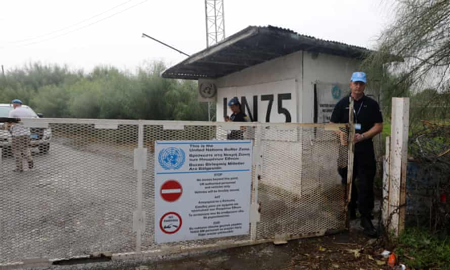 A UN soldier opens a gate leading into the buffer zone in Cyprus