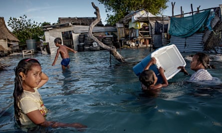 Children play amid flooded homes in Kiribati, now under threat from rising sea levels