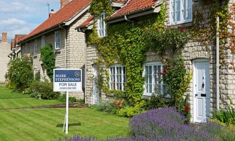 House for sale sign in lawn of house in village