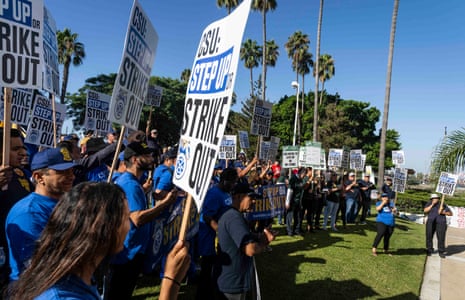 Protesters under palm trees with signs saying 'CSU: Step up or strike out'.