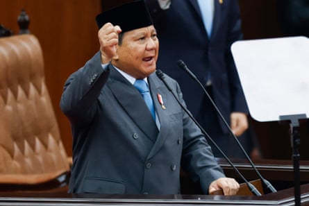 Prabowo raises his fist while speaking at a podium microphone