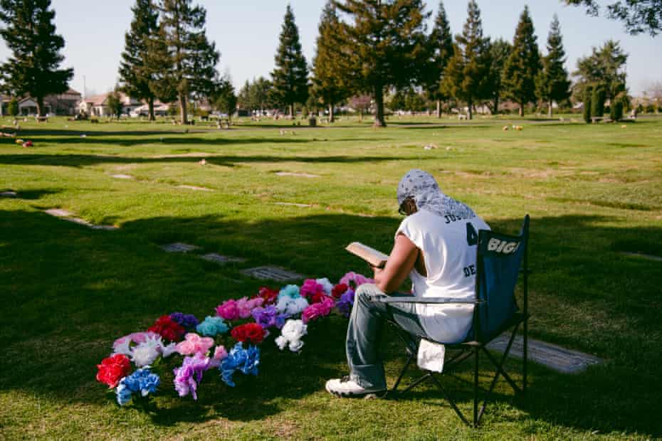 David Phillips reads a Bible verse while visiting the grave of his son, Desmond Phillips, at Saint Mary Cemetery.