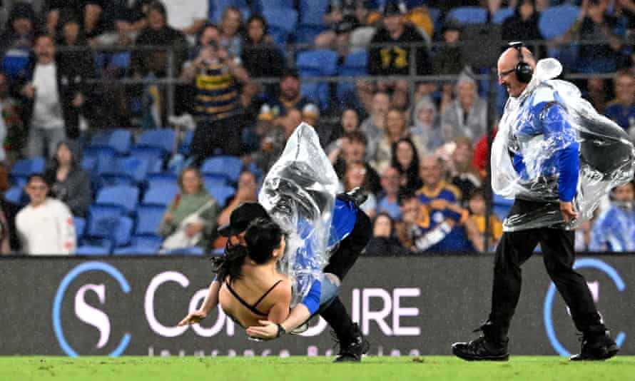 The pitch Invader is tackled by a security guard at Cbus Super Stadium.