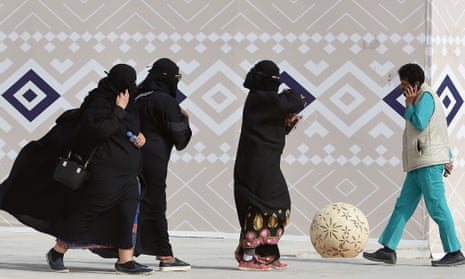 Three women in burqas and a man holding a mobile phone to his ear in Rumah, Saudi Arabia
