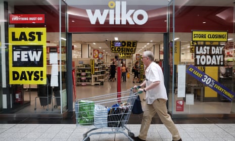 a shopper passes a wilko store with its closing down signs