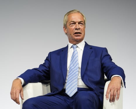 Nigel Farage speaks as he sits on stage in a chair