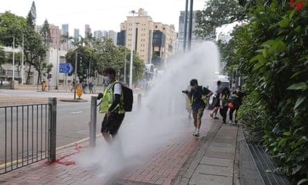 Journalists run as police fire a water cannon at marchers
