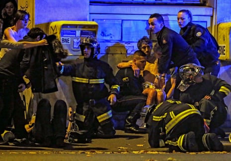 French fire brigade members aid an injured individual near the Bataclan concert hall following fatal shootings in Paris on 13 November 2015