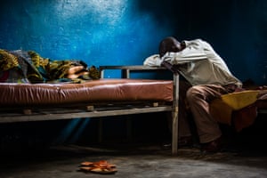 A man rests next to his bedridden wife, who is suffering from malaria, at the Saint Martyr health centre in Kananga