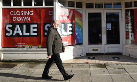 A man walks past signs for a closing down sale in Newcastle-Under-Lyme, Staffordshire