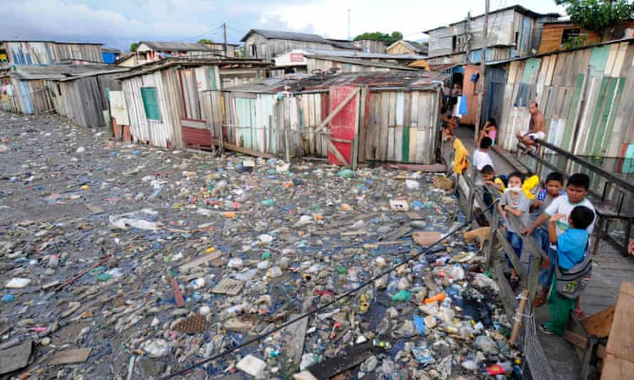 Residents of the Betania slum use a makeshift walkway to avoid garbage floating on floodwaters in Manaus.