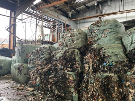 Huge bales of waste in a barn or industrial unit.