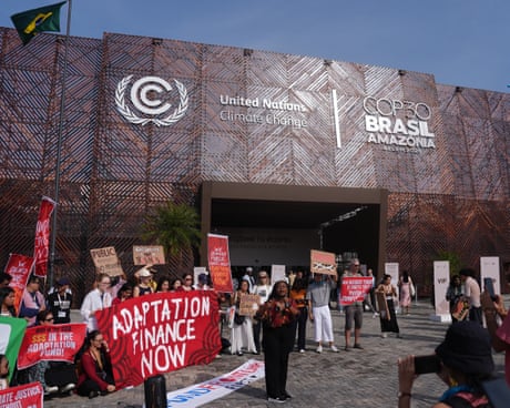 A small crowd of people holding flags and signs outside the entrance to the summit